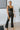 Front view of model wearing the Daily Ritual Faded Jeans, which have a stretchy denim material, a faded black wash, a flare leg fit, a high-rise waist, a five button closure, two front pockets, a frayed/distressed flare hem, and two back pockets