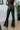 Back view of model wearing the Daily Ritual Faded Jeans, which have a stretchy denim material, a faded black wash, a flare leg fit, a high-rise waist, a five button closure, two front pockets, a frayed/distressed flare hem, and two back pockets