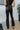 Back view of model wearing the Daily Ritual Faded Jeans, which have a stretchy denim material, a faded black wash, a flare leg fit, a high-rise waist, a five button closure, two front pockets, a frayed/distressed flare hem, and two back pockets