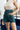 Close-up front view of model wearing the Upper East Side Shorts, which have a green corduroy material, a high-rise waist, gold button embellishments on the front, and two front pockets