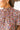 Frontal view of the Sun Chasing Top that features a floral print, a high neckline, a short puffy sleeve, and a back neck tie.