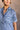 Upper front view of model wearing the Aubrie Washed Blue Short Sleeve Mini Dress that has washed light blue chambray fabric, a chest pocket, a hidden quarter button-up, a v neck, a collar, a frayed hem, and cuffed short sleeves.