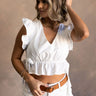 Front view of model wearing the Lucie White Ruffle Peplum Top that has white cotton fabric, a peplum body, ties on each side with an elastic waistband, a v-neckline, and short sleeves with ruffle details.