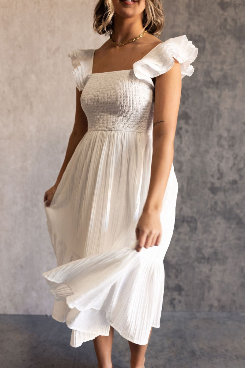 Front view of model wearing the Katherine Off White Sleeveless Midi Dress which features white fabric with stitched stripe details, a smocked upper with a straight neckline, layered ruffled straps, white lining, and a midi-length hem.