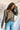 Front view of model wearing the Lost Without You Sweater, which features olive open-knit fabric with larger knitting on the sides, a round neckline, long sleeves, and a slouchy fit.