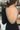 Close-up back view of model wearing the Date Night Midi Dress, that has black ribbed knit fabric, a plunge back with pearl and rhinestone trim, a high round neckline, long fitted sleeves, a side slit.