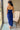 Back view of model wearing the Turn Back Time Midi Dress, which features lined navy fabric, a strapless corset top with boning in the front, a front slit, and a back zipper
