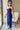 Side view of model wearing the Turn Back Time Midi Dress, which features lined navy fabric, a strapless corset top with boning in the front, a front slit, and a back zipper