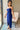 Side view of model wearing the Turn Back Time Midi Dress, which features lined navy fabric, a strapless corset top with boning in the front, a front slit, and a back zipper