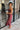 Side view of model wearing the Magic Moment Dress in Burgundy, which features satin fabric with a midi-length hem, burgundy feathers across the neckline, adjustable thin straps, and a back zipper