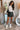 Full body front view of model wearing the Talk That Talk Skort, which features black faux-leather with silver studs, a front skirt overlay, and a back zipper.