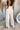 Back view of model wearing the Isabella Corduroy Pants, that feature lightweight cream-colored corduroy, a button + zipper closure, front and back pockets, and wide legs