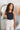 Upper front view of model wearing the Isabella Corduroy Pants, that feature lightweight cream-colored corduroy, a button + zipper closure, front and back pockets, and wide legs