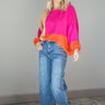 Full body front view of model wearing the Noa Color Block Long Sleeve Sweater that has a pink, yellow, and orange color block pattern, long balloon sleeves with ribbed wrists, a round neckline, and oversized fit.