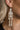 Side view of model wearing the Sally White Glitter Skeleton Earrings that feature white glitter skeleton shaped dangle earrings with gold link details.