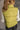 Back view of model wearing the Mckenna Chartreuse Puffer Vest that has yellow-green puffer fabric, a zip-up front with a high neckline, and front slit pockets.
