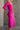 Side view of model wearing the Dahlia Pink One-Shoulder Ruched Midi Dress that has lightweight pink knit fabric, a one-shoulder neckline with 1 long sleeve, a back cutout, ruched sides, and a side slit.