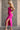 Side view of model wearing the Dahlia Pink One-Shoulder Ruched Midi Dress that has lightweight pink knit fabric, a one-shoulder neckline with 1 long sleeve, a back cutout, ruched sides, and a side slit.