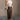 Full body view of model wearing the Angela Brown Front Slit Midi Skirt which features brown cotton fabric, midi length, front slit detail, front zipper with button closure, belt loops, two front pockets, two back pockets and fray hem.