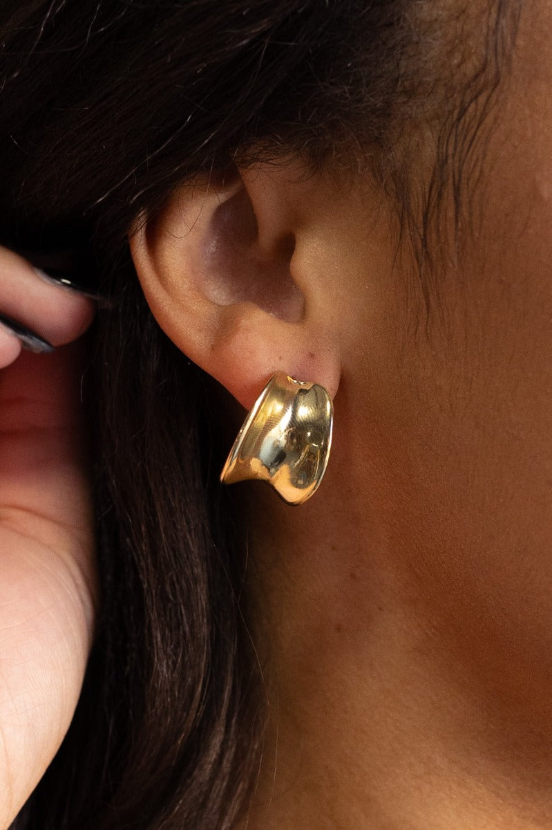 Close-up view of model wearing the Kinsley Gold Earrings that feature gold dimensional scooped studs.