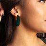 Side view of model wearing the Sadie Green Velvet Hoop Earrings that feature medium open hoops with dark green velvet fabric.