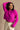 Front view of model wearing the Aria Fuchsia Long Sleeve Sweater which features fuchsia textured knit fabric, ribbed trim, a cropped waist, a round neckline, dropped shoulders, and long sleeves with ribbed trim.