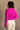 Back view of model wearing the Aria Fuchsia Long Sleeve Sweater which features fuchsia textured knit fabric, ribbed trim, a cropped waist, a round neckline, dropped shoulders, and long sleeves with ribbed trim.