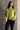 Front view of model wearing the Ellie Pale Olive Long Sleeve Sweater which features pale green knit fabric with a monochrome ribbed geometric design, ribbed thick hem, a round neckline, dropped shoulders, and long sleeves with cuffs.