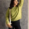 Front view of model wearing the Ellie Pale Olive Long Sleeve Sweater which features pale green knit fabric with a monochrome ribbed geometric design, ribbed thick hem, a round neckline, dropped shoulders, and long sleeves with cuffs.