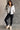 Full body view of model wearing the Adelaide Light Blue Puffer Jacket which features pale blue puffer fabric with tufted details, a monochrome button up front with a high neckline, two front slit pockets and long sleeves.
