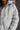 Close up view of model wearing the Adelaide Light Blue Puffer Jacket which features pale blue puffer fabric with tufted details, a monochrome button up front with a high neckline, two front slit pockets and long sleeves.