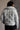 Back view of model wearing the Adelaide Light Blue Puffer Jacket which features pale blue puffer fabric with tufted details, a monochrome button up front with a high neckline, two front slit pockets and long sleeves.