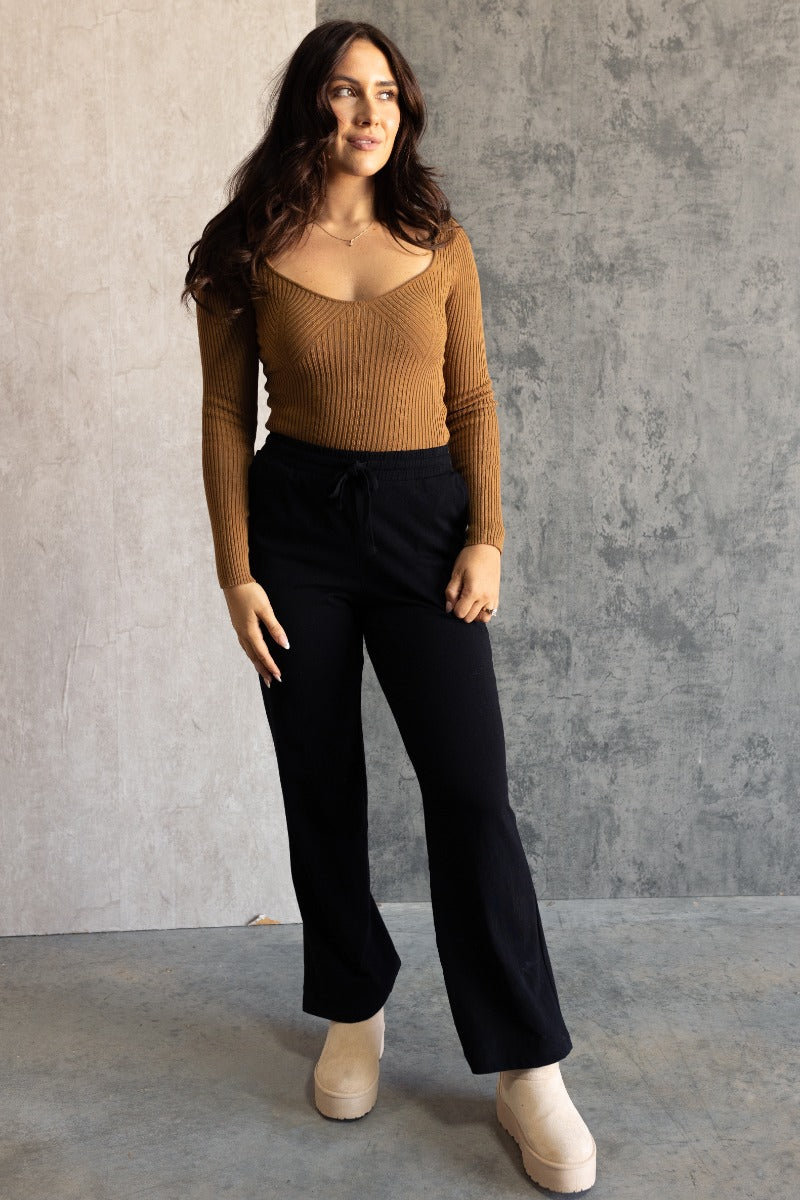 Full body view of model wearing the Aubrey Black Lounge Pants which features black cotton fabric, two front pockets, an elastic waistband with drawstring ties, and wide legs.