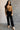 Full body view of model wearing the Aubrey Black Lounge Pants which features black cotton fabric, two front pockets, an elastic waistband with drawstring ties, and wide legs.