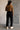 Full body back view of model wearing the Aubrey Black Lounge Pants which features black cotton fabric, two front pockets, an elastic waistband with drawstring ties, and wide legs.