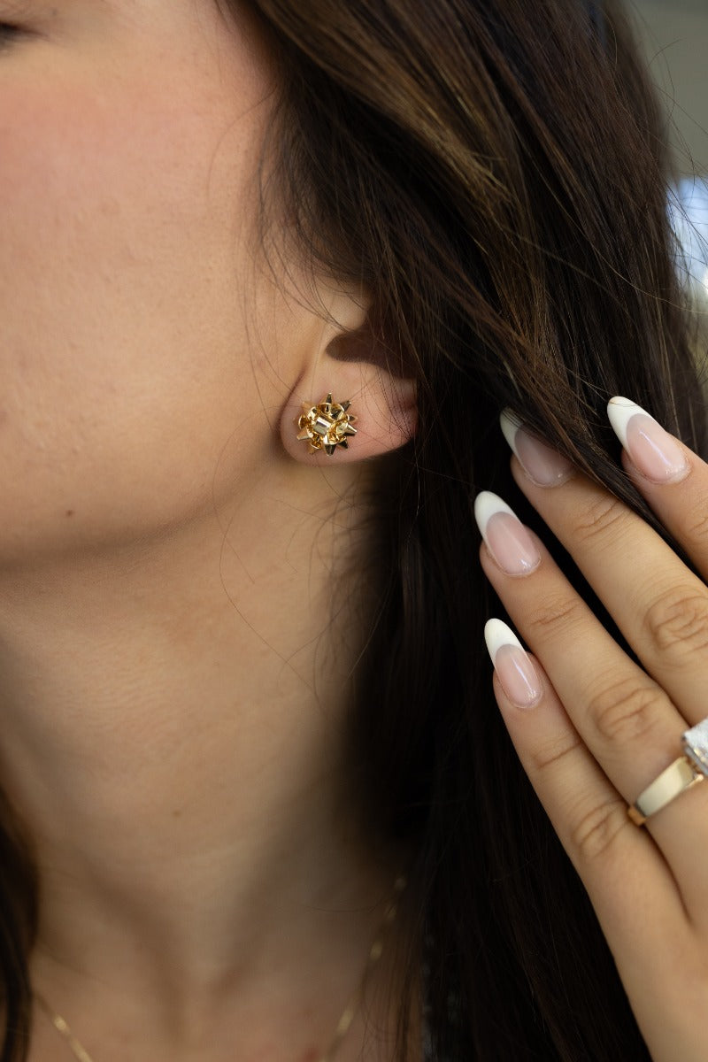 Side view of model wearing the Cora Gold Bow Stud Earrings that feature small gold studs shaped as a present bow.