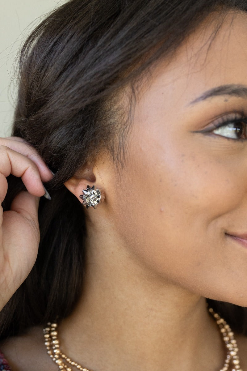 Side view of model wearing the Bella Silver Bow Stud Earrings that feature silver studs shaped as a present bow.