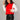 Fontal side view of model wearing the Nora Red Cropped Zip-Up Puffer Vest which features red puffer fabric, monochrome front zip up, high neckline with ruffle details, two front slit pockets and sleeveless.