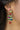 Close-up of model wearing the Christmas Tree Multi-Color Stone Earrings that have multi-colored stones forming a Christmas Tree shape with green stars on post backs and red gift pendants.