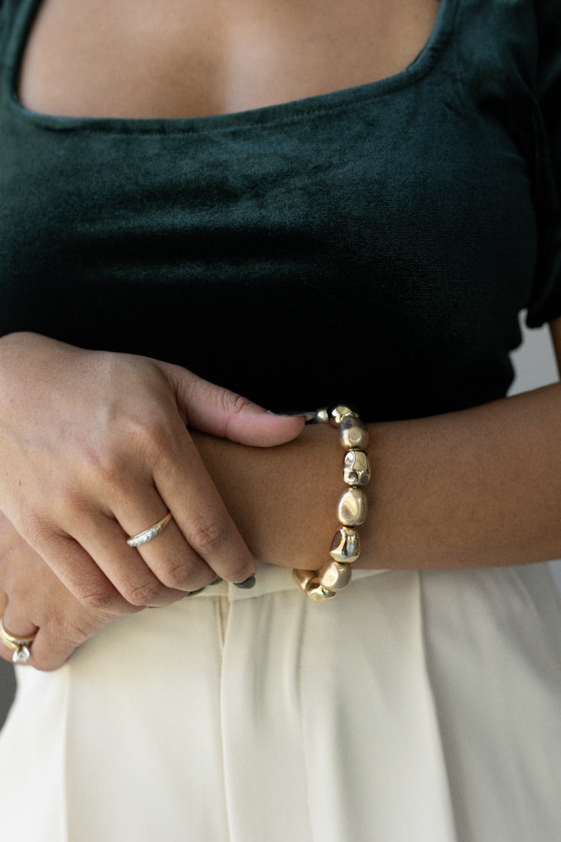 Close-up of model wearing the Elena Hammered Gold Beaded Bracelet that features one stretchy layer with large hammered matte & shiny gold beads.