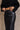 Close upper front view of model wearing the Danna Black Faux-Leather Slit Front Midi Skirt that has black faux leather, a zip up front, a front slit, two front pockets, and midi length.