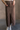 Front view of model wearing the Angela Brown Front Slit Midi Skirt which features brown cotton fabric, midi length, front slit detail, front zipper with button closure, belt loops, two front pockets, two back pockets and fray hem.