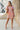 Full body front view of model wearing the Under The Cabana Dress that has blue, green, orange, pink and yellow fabric with a floral pattern, ivory lining, a sweetheart neck, an elastic waist, a smocked back, and short bubble sleeves