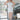 Full body front view of model wearing the All Eyes On Me Dress that has white sheen fabric, white lining, mini length, an overlapped hem, one shoulder strap, and a monochromatic back zipper.