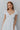 Upper front view of model wearing the Make A Wish Dress in White that has white fabric, white lining, a tiered body style, a v-neckline, a smocked back and short puff sleeves with elastic bands
