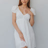Front view of model wearing the Make A Wish Dress in White that has white fabric, white lining, a tiered body style, a v-neckline, a smocked back and short puff sleeves with elastic bands