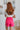 Back view of model wearing the Brighten My Day Shorts that have hot pink fabric, a high-rise waist with smocked details, and hot pink panty lining.