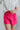 Close front view of model wearing the Brighten My Day Shorts that have hot pink fabric, a high-rise waist with smocked details, and hot pink panty lining.