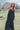 Front view of model wearing the Definitely You Maxi Dress which features black fabric, maxi length, multi tiered body. v neckline and double spaghetti straps that cross in the back.