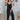 Full body view of model wearing the Stepping Out Jumpsuit which features black fabric, v-neckline, spaghetti strap ties and long flare pants.